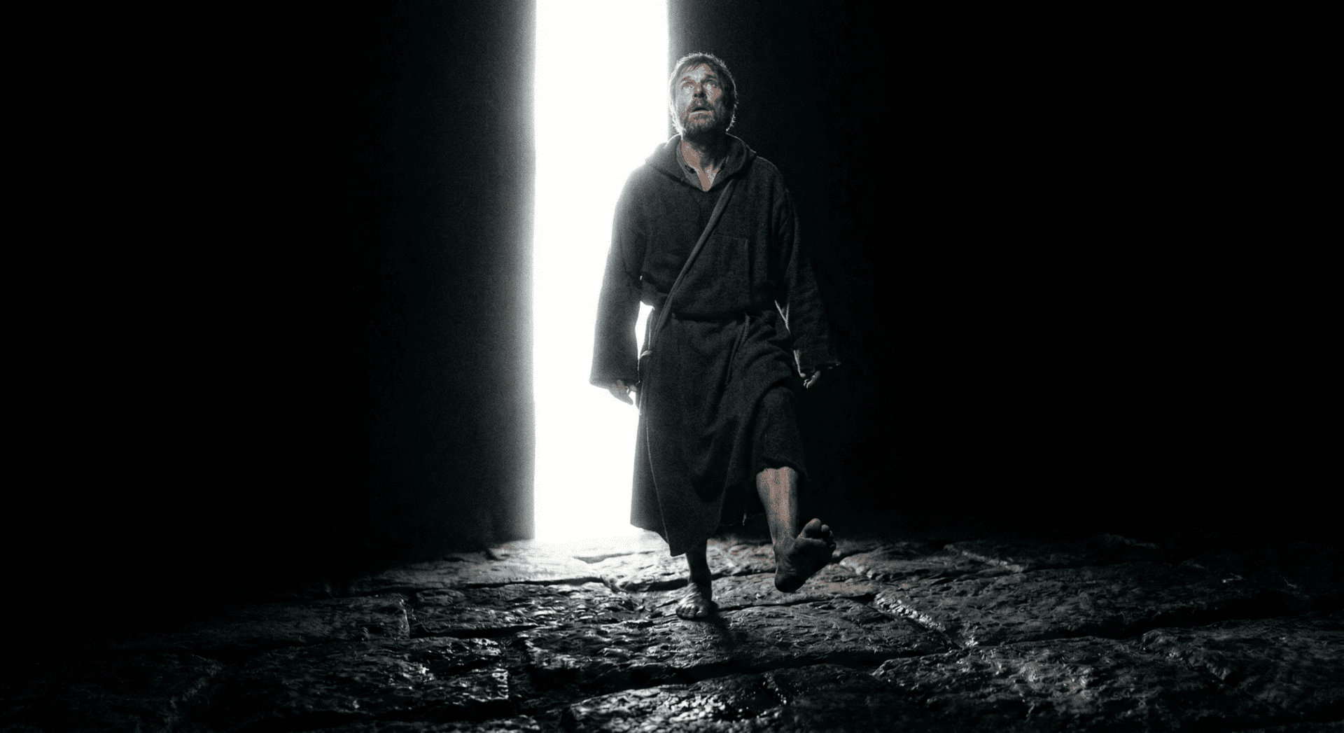 Um iniciado maçônico saindo da escuridão para uma luz brilhante, simbolizando o despertar da consciência e a busca pelo conhecimento.